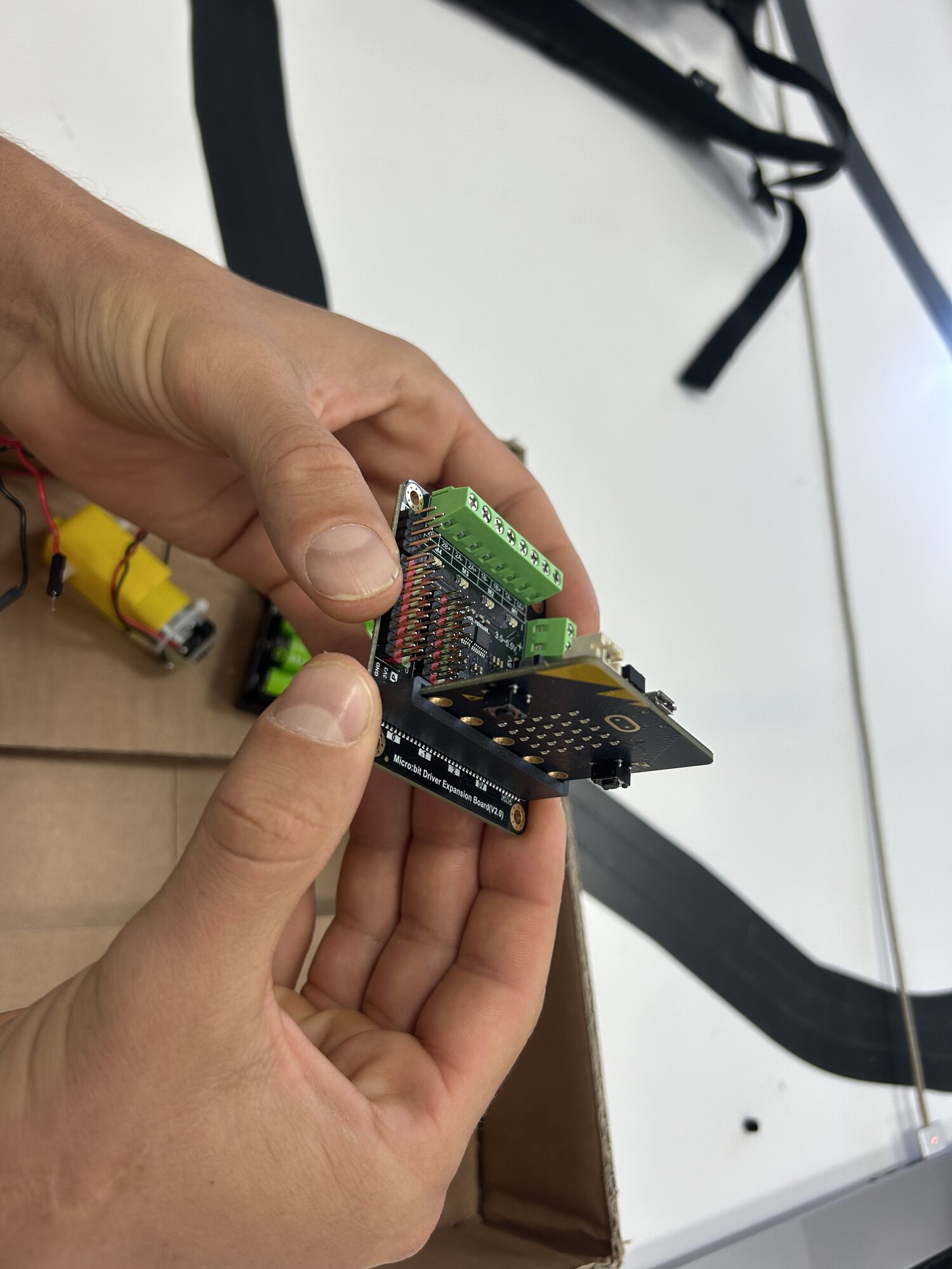 Le micro:bit en train d'être enfiché dans le connecteur de la carte d'extension, écran vers l'extérieur
