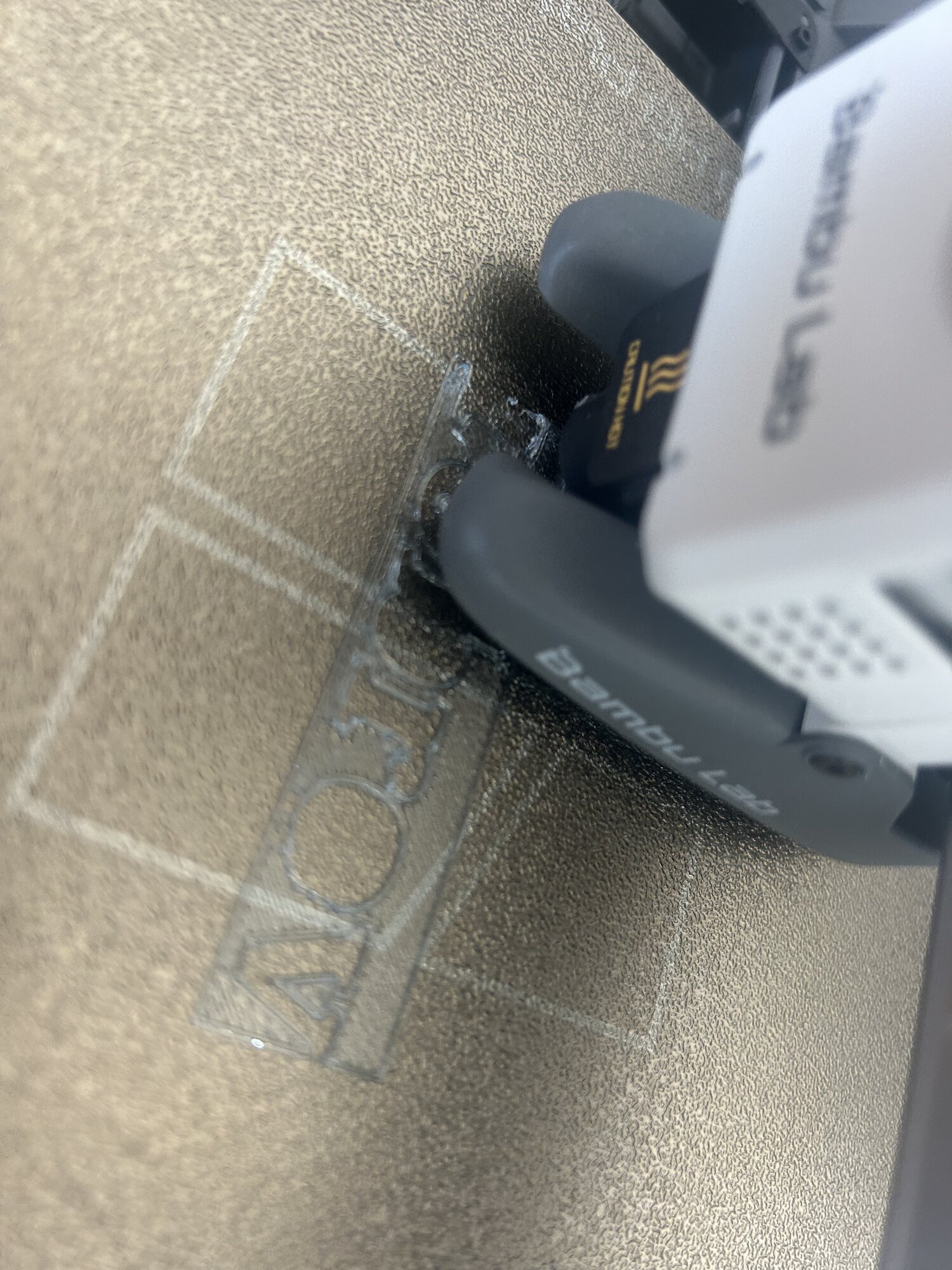 La première couche de la plaque en cours d'impression, la buse de l'imprimante en train de déposer le plastique