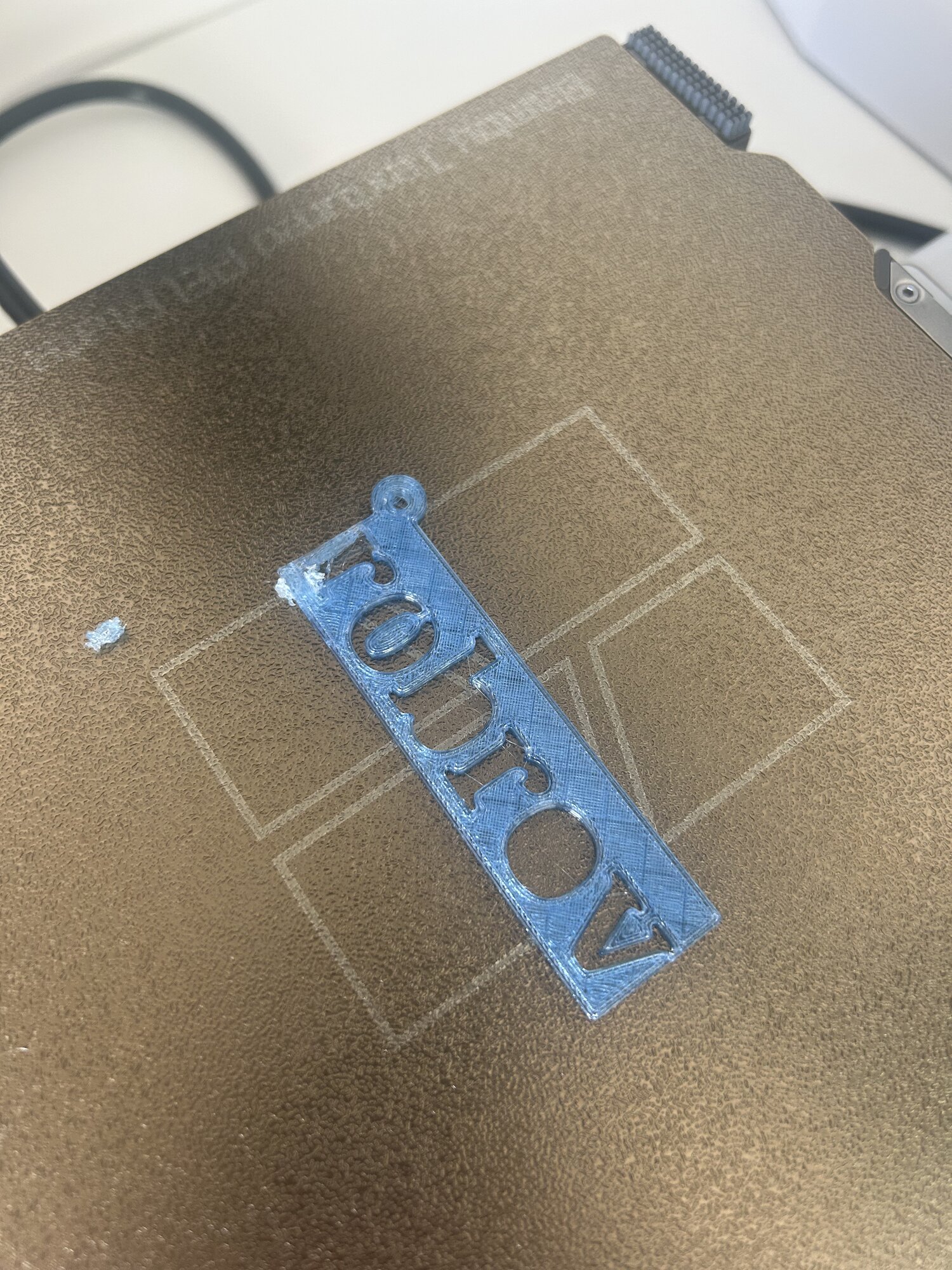 La plaque bleue terminée sur le plateau de l'imprimante, le nom robrov découpé dedans