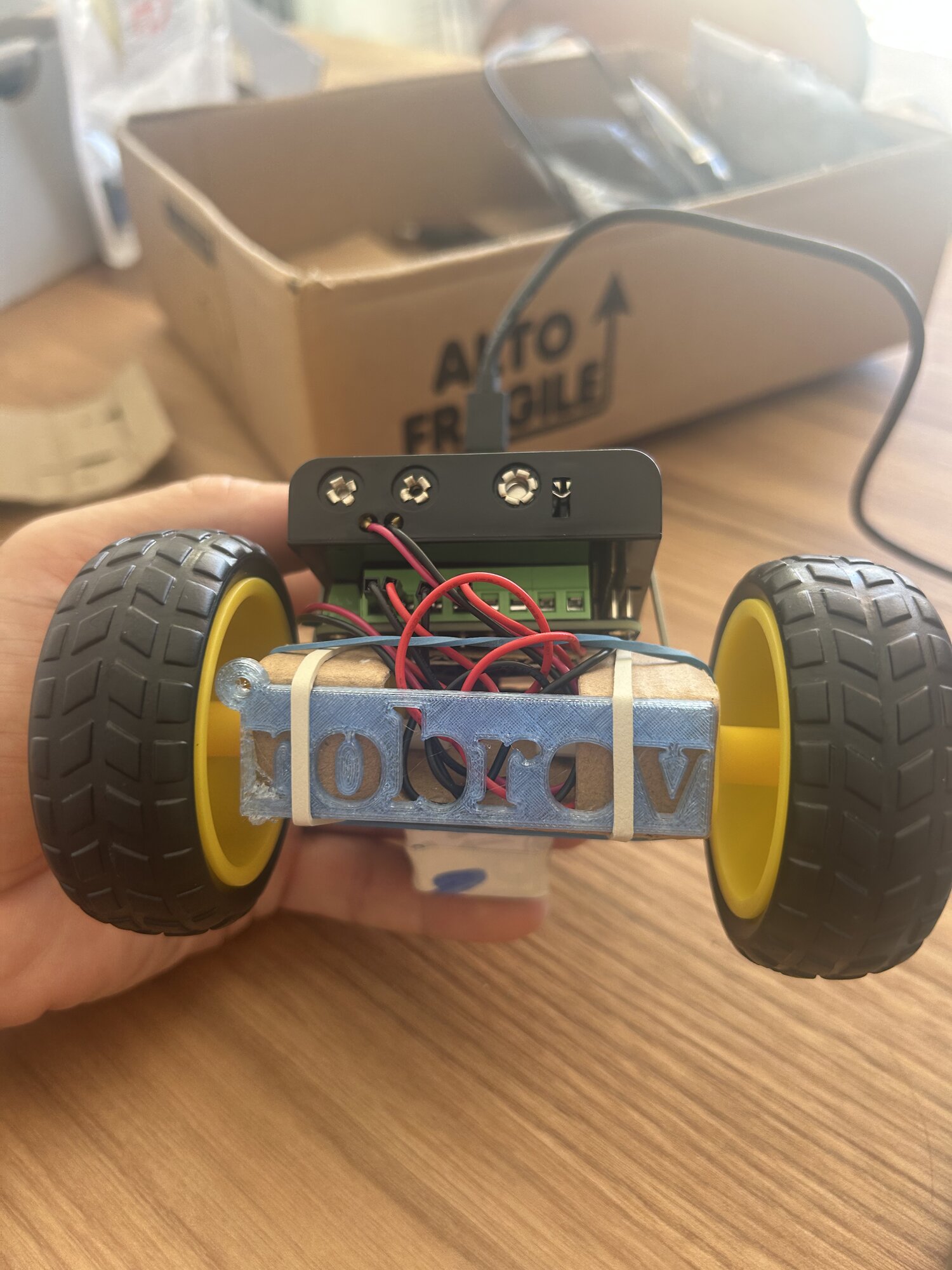 La plaque sanglée par deux élastiques à l'avant du rover, entre les deux roues